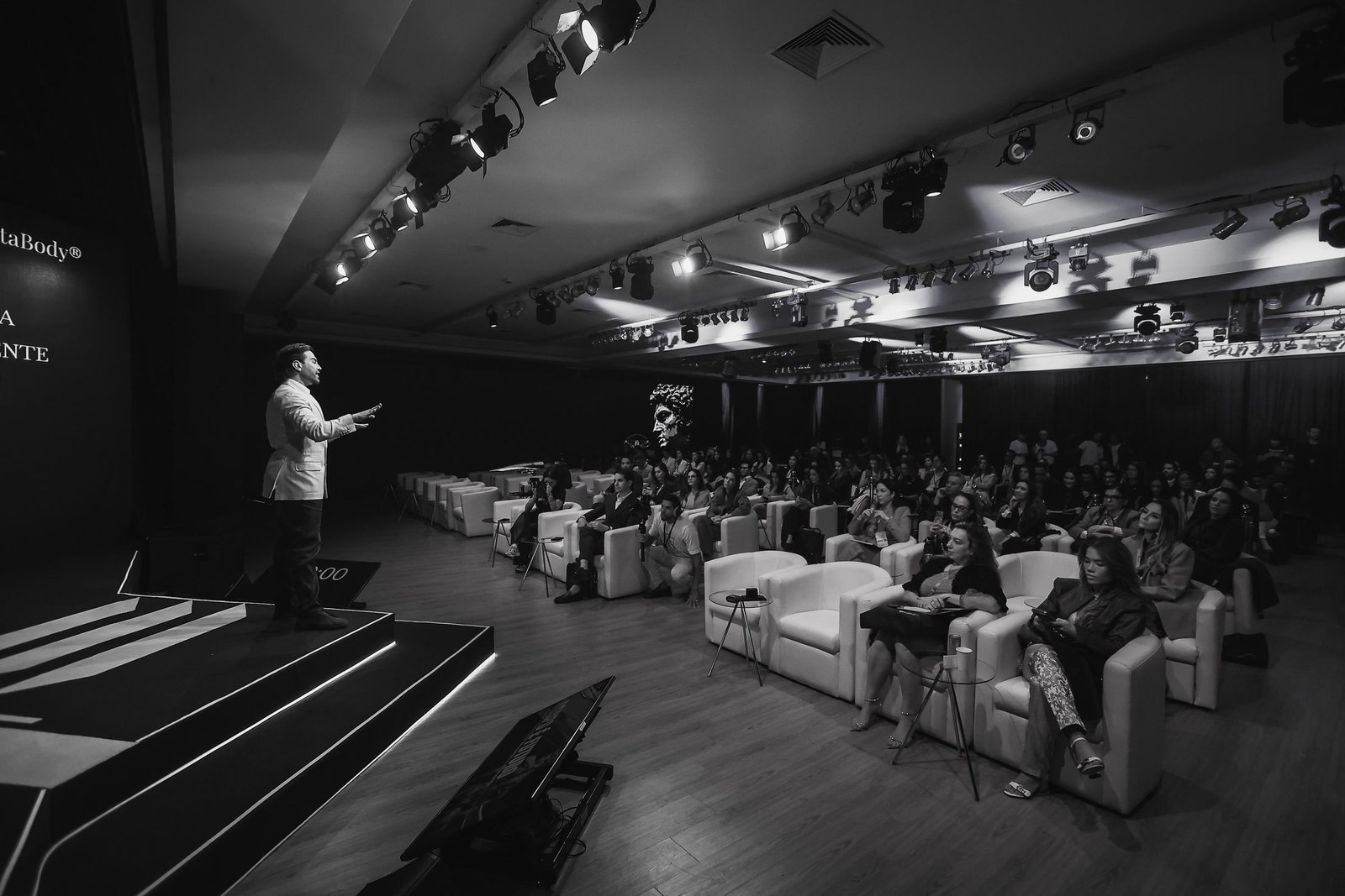 Dr. Matheus Arantes no palco, durante uma formação para médicos